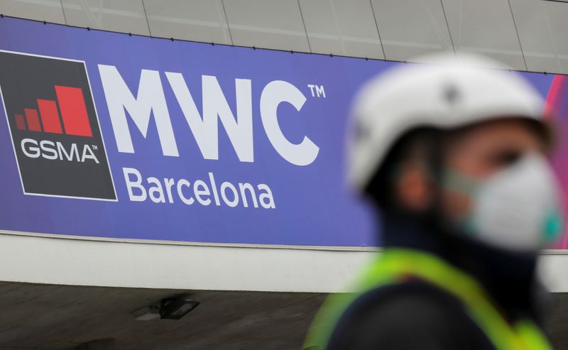 FILE PHOTO: Employee is pictured next to the logo of the cancelled event MWC20 (Mobile World