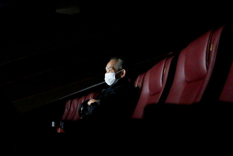 FILE PHOTO: A man wears a protective mask as he watches a movie, following the outbreak of the