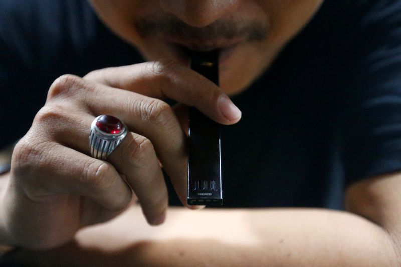 A man smokes Juul vaping product at a vape shop in Jakarta