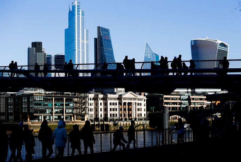 FILE PHOTO: London's financial district can be seen behind people crossing Millennium Bridge