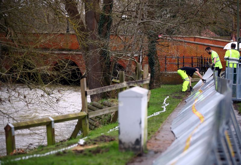 Environment Agency workers install temporary flood barriers along the bank of the River Mole in