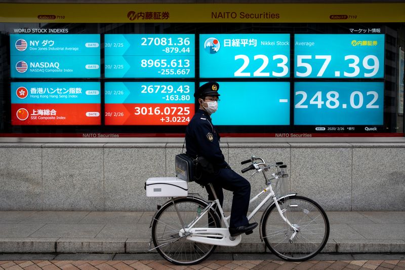 A man is reflected on a stock quotation board outside a brokerage in Tokyo