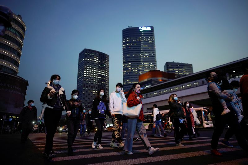 People wearing protective face masks are seen on a crossroad following the outbreak of