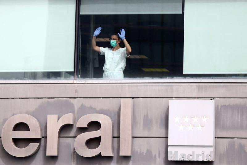 Medical staff in protective gear wave from the Intensive Care Unit of La Paz Hospital in Madrid