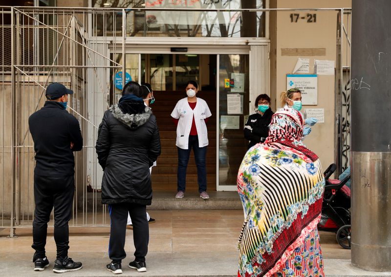 People stand in a queue to enter into a Medical Center, as medical staff check them, during an