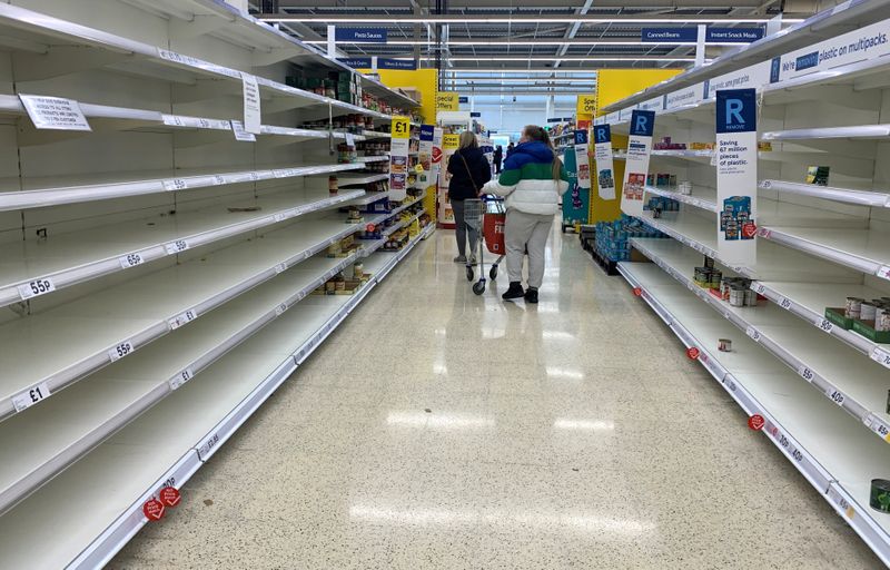 A customer walks past a sign informing shoppers about limited stock inside a Tesco supermarket,