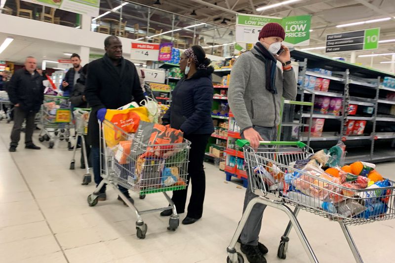 Shoppers walk past empty shelves inside a Tesco supermarket in Liverpool