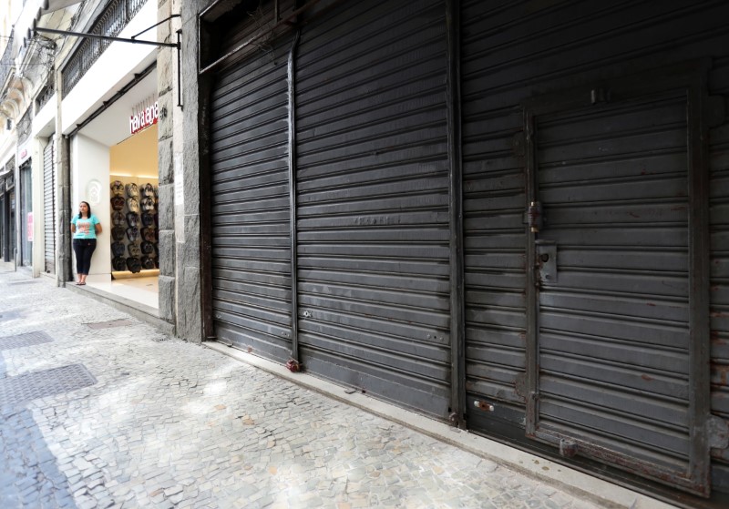 A man wearing a protective mask outside Rocinha Slum waits for a public bus during the