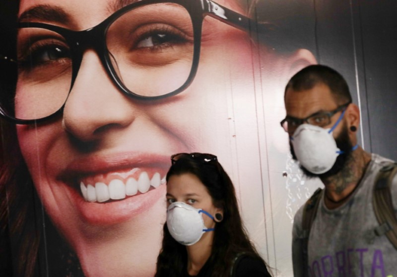 People wear protective face masks at international arrivals area at Guarulhos International