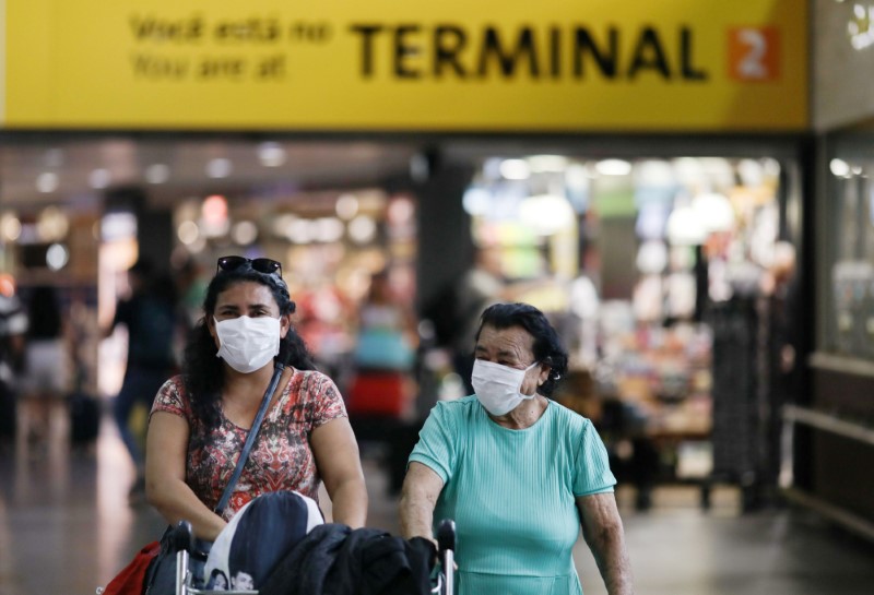 People wear protective face masks at international arrivals area at Guarulhos International