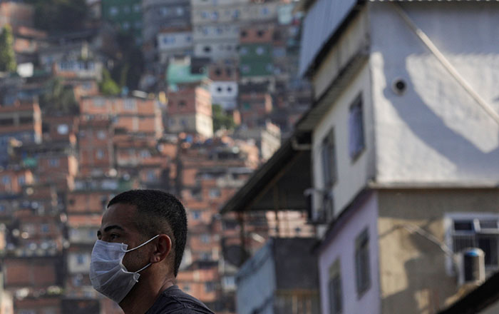 A man wearing a protective mask outside Rocinha Slum waits for a public bus during the
