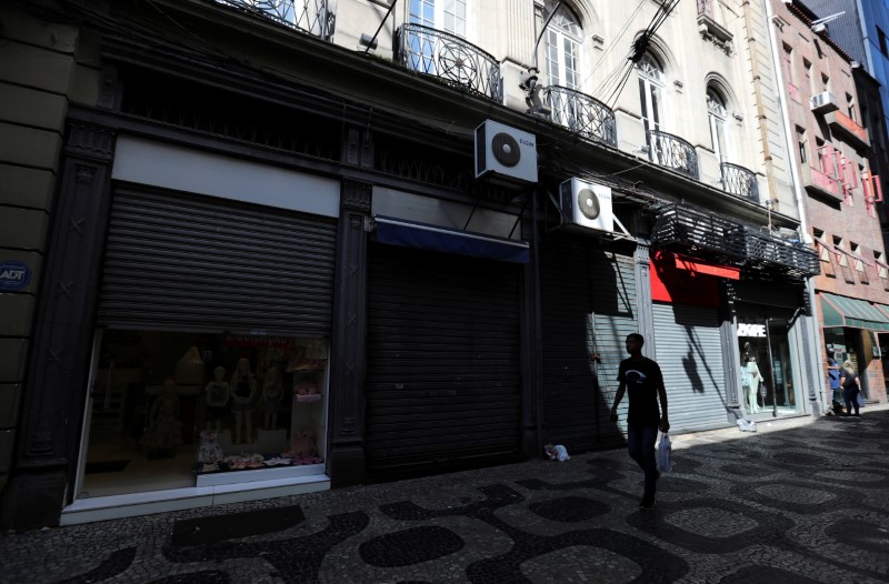 A vendor stands next to a partially closed shop after authorities announced measures to curb