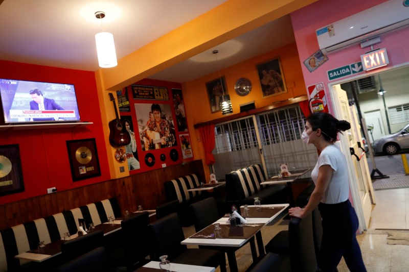 A waitress watches the TV as she waits for costumers in a restaurant, following the outbreak of