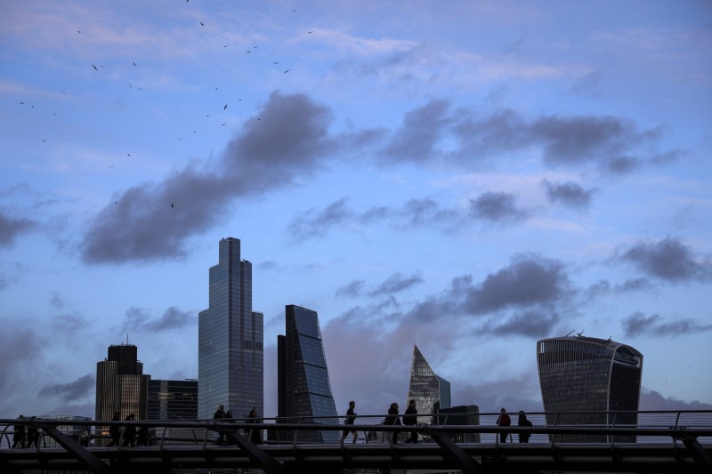 FILE PHOTO: Pedestrians walk over the Millennium Bridge in view of skyscrapers in the financial