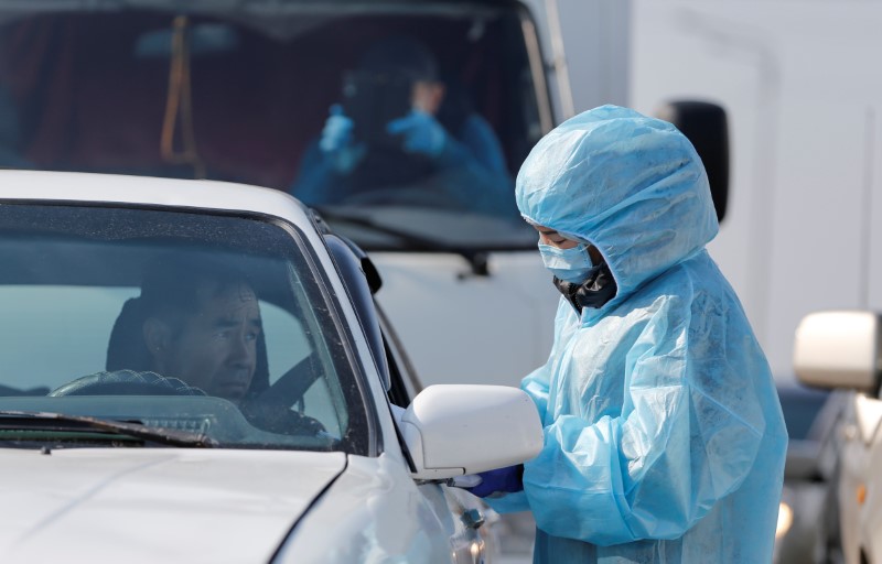 A Chinese woman, wearing full protective gear to prevent contracting the coronavirus, waits for