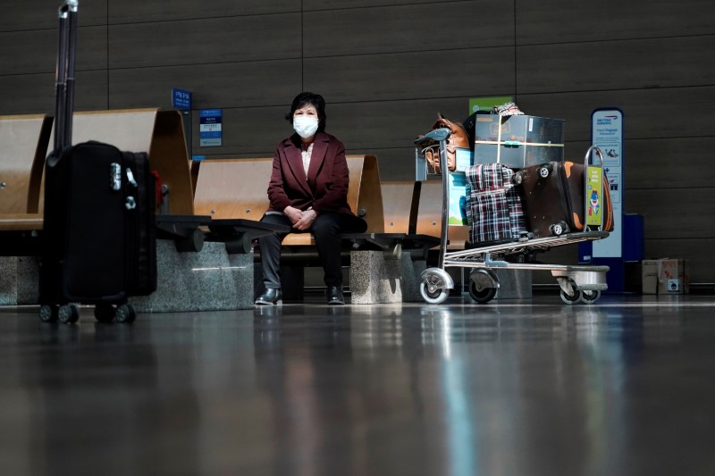 A woman wearing a mask to prevent contracting the coronavirus waits for her flight at Incheon