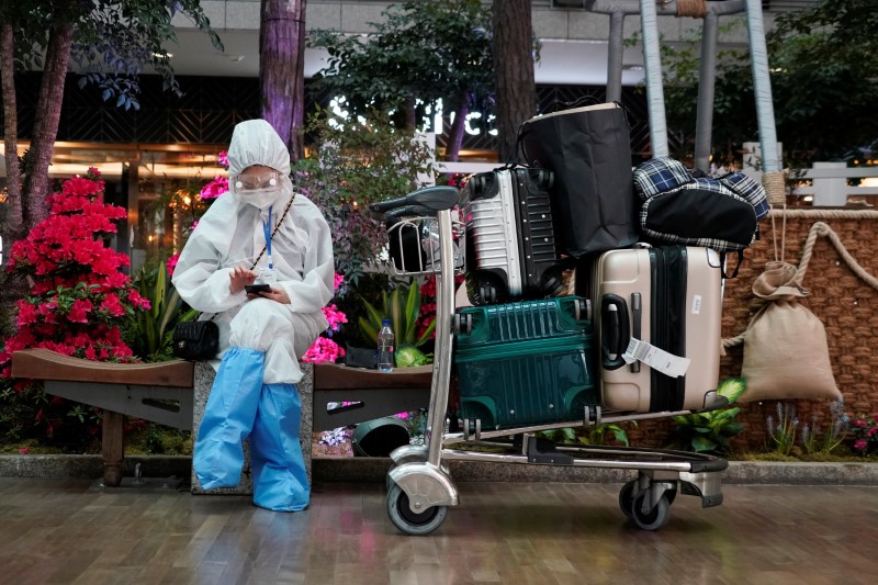 A Chinese woman, wearing full protective gear to prevent contracting the coronavirus, waits for