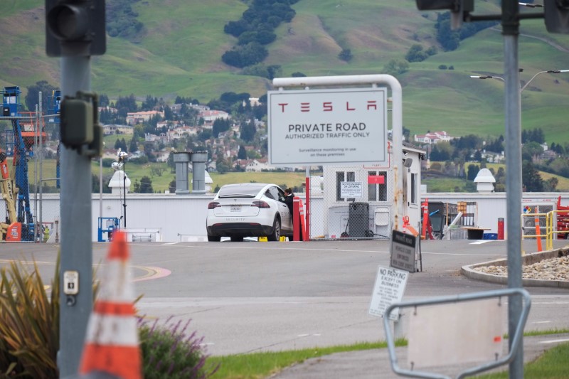 An employee of a Tesla Inc's U.S. vehicle factory is seen at a security gate in Fremont,