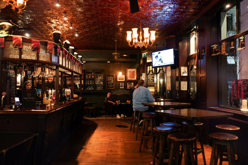 FILE PHOTO: People drink inside a quiet Irish pub in Soho, as the number of coronavirus