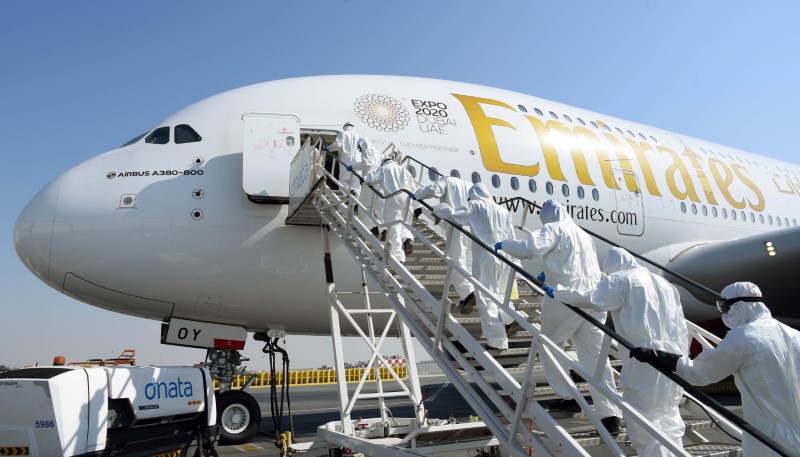 Members of cleaning staff in protective suits board an Emirates Airbus A380 to disinfected it