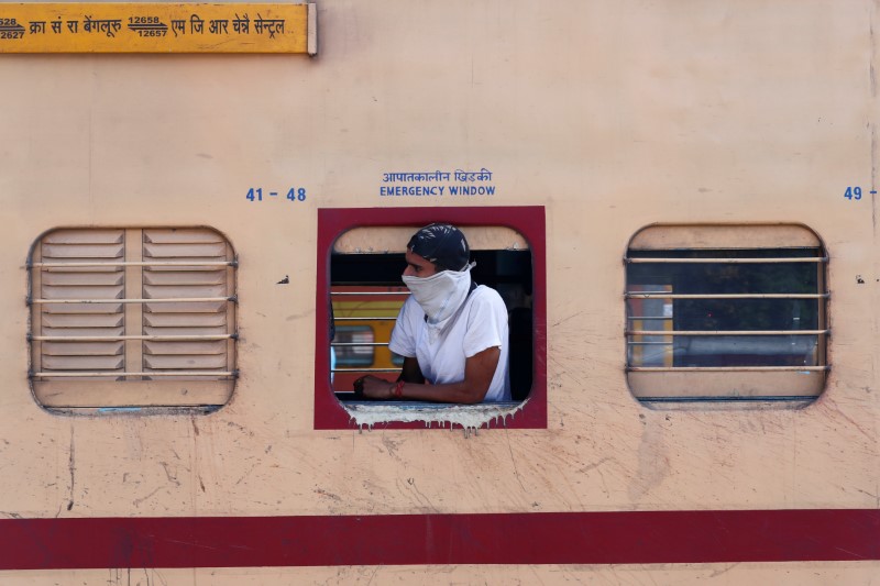 A man with his face covered looks out from a train during lockdown by the authorities to limit