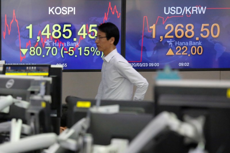 A currency dealer walks past in front of electronic boards showing the Korea Composite Stock
