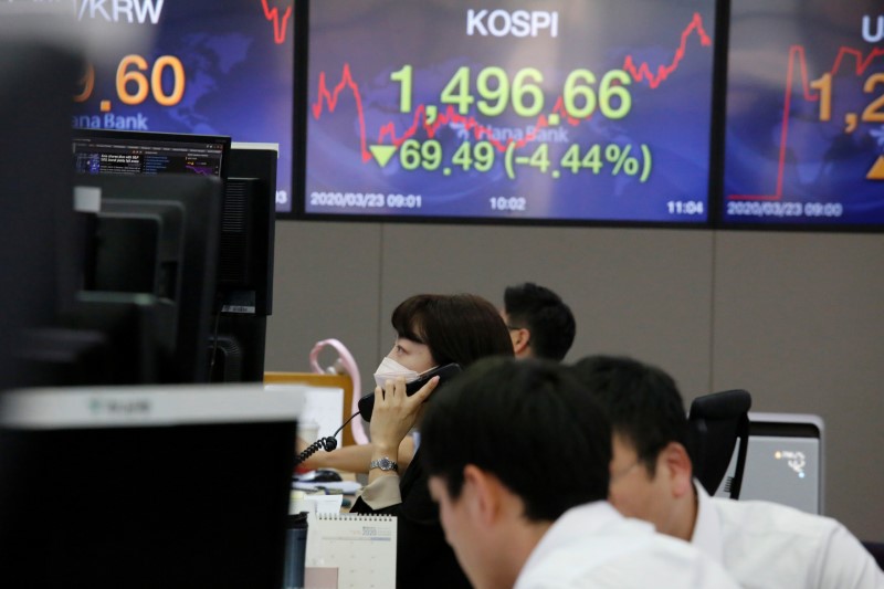 A currency dealer walks past in front of electronic boards showing the Korea Composite Stock
