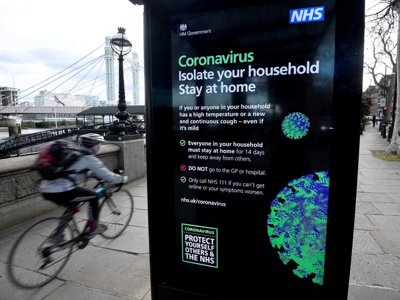 FILE PHOTO: A cyclist rides past a UK government public health campaign poster as the spread of
