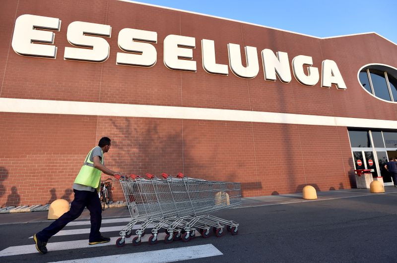FILE PHOTO: A man pushes shopping carts outside Esselunga supermarket in Pioltello near Milan