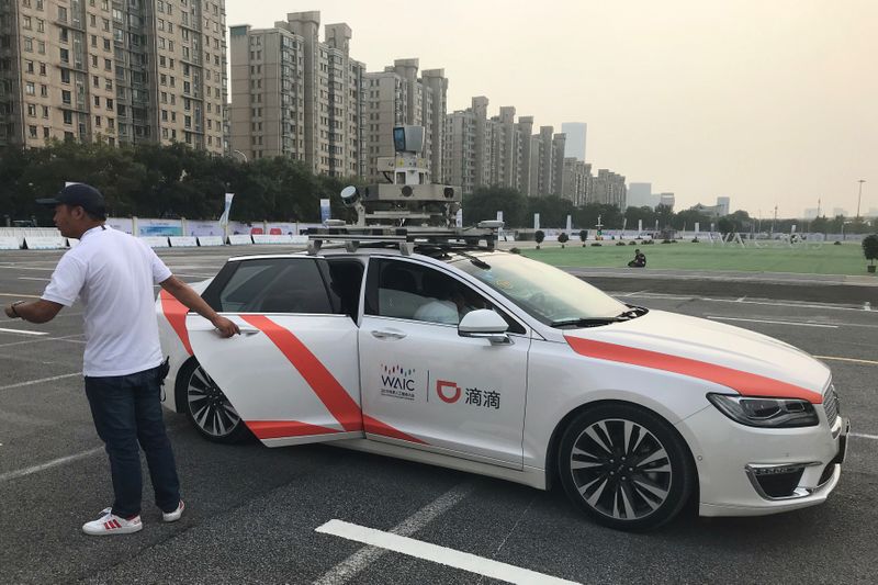 FILE PHOTO: Man holds a door to a Didi self-driving car during the World Artificial