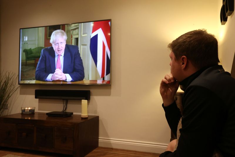 FILE PHOTO: A man watches British Prime Minister Boris Johnson's press conference as the spread