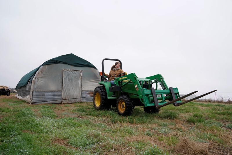 Ward opens a bag of feed on his farm in Pawnee