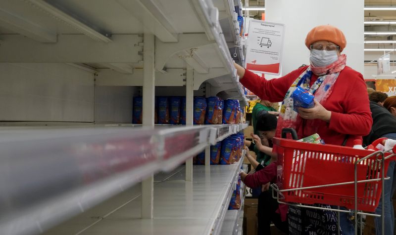 FILE PHOTO: A woman, wearing a protective mask, holds a pack of buckwheat from a new delivery,