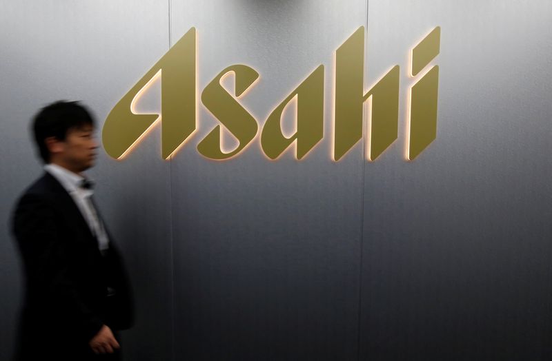 Man walks past the logo of Asahi Group Holdings at the company's headquarters in Tokyo
