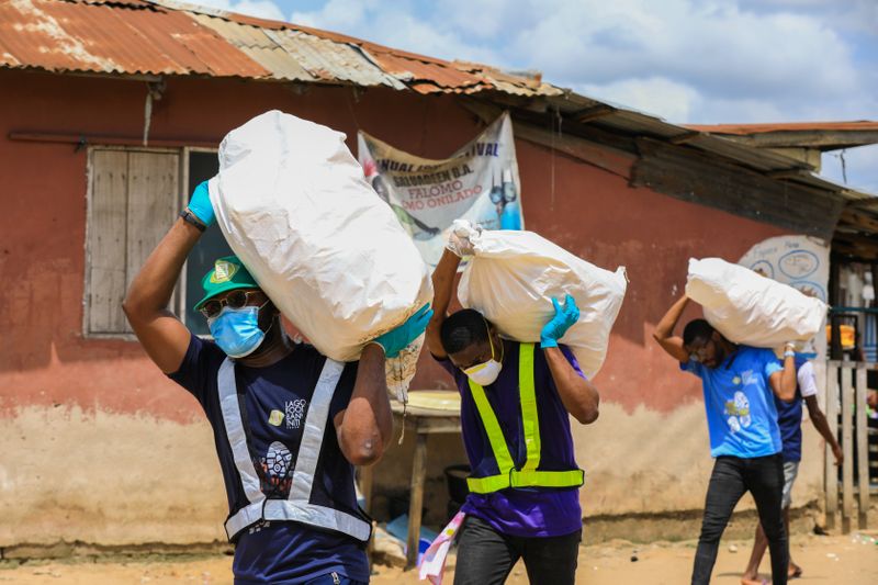 Volunteers carry sacks filled with food to distribute to vulnerable residents, during a