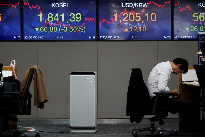 FILE PHOTO: A currency dealer looks at his mobile phone in front of electronic boards showing