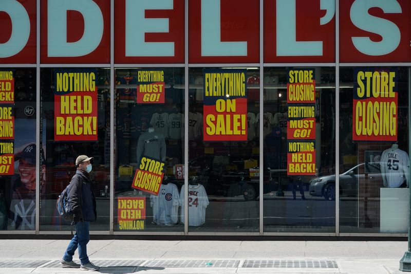 A man stands in front of a Modell's store that is closed, as retail sales suffer record drop
