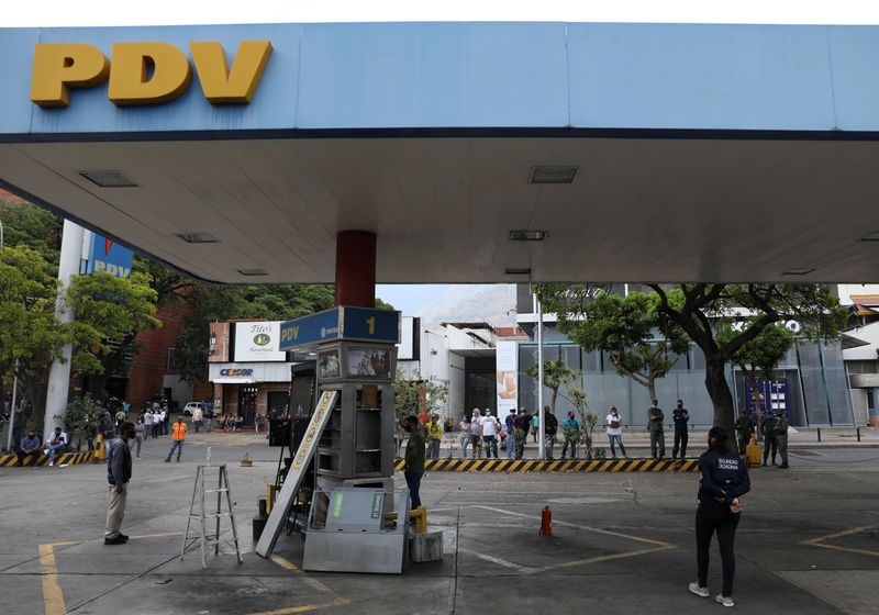 FILE PHOTO: Customers wait while a fuel dispenser machine is fixed at a gas station in Caracas