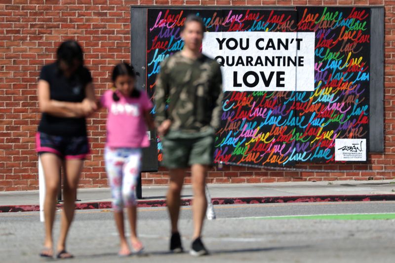 People walk in front of a mural, as the global outbreak of the coronavirus disease (COVID-19)