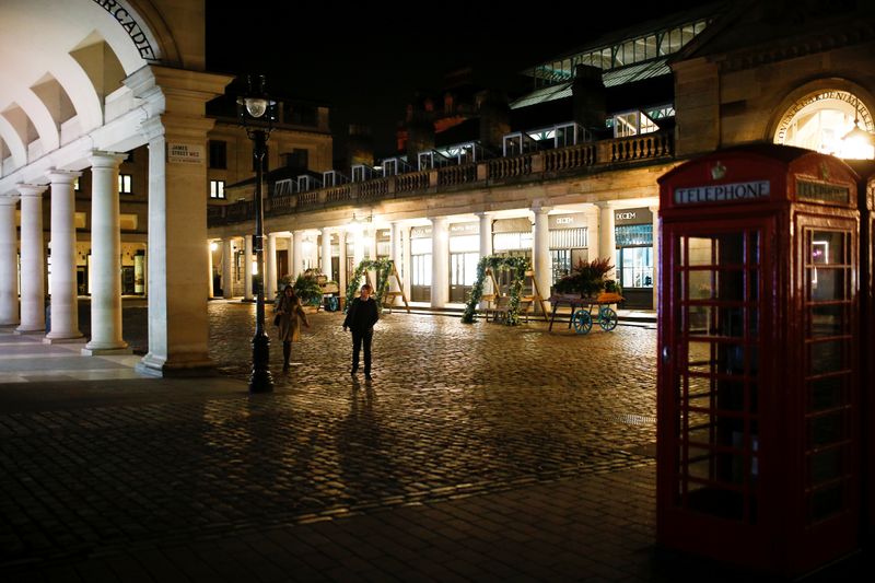A couple walk through a deserted Covent Garden as venues close following growing number of