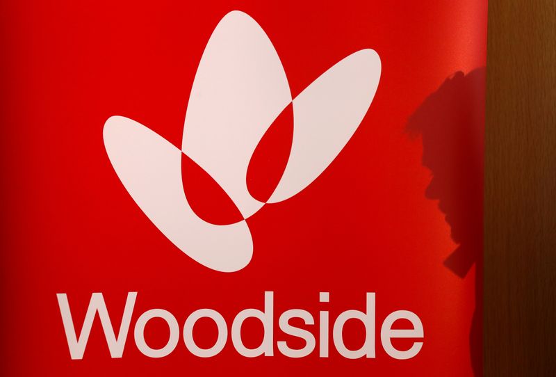 FILE PHOTO: The shadow of a man is cast onto a poster displaying the logo for Woodside