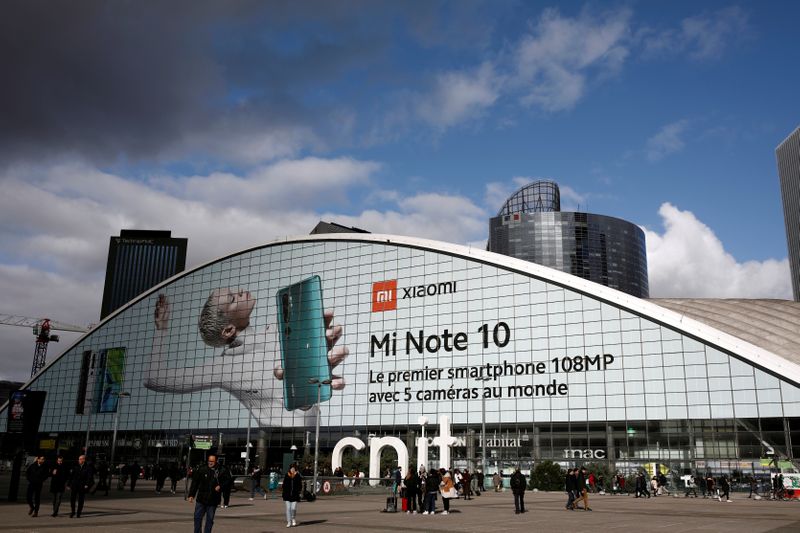 FILE PHOTO: Pedestrians walk past an advertisement for Xiaomi Mi Note 10 smartphone at the