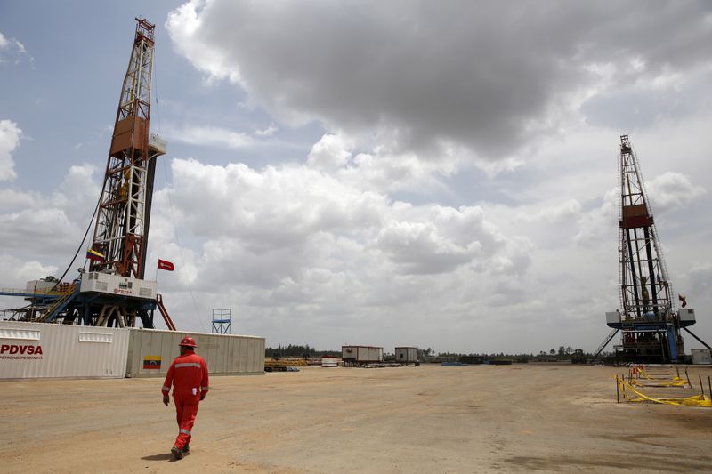 FILE PHOTO: An oilfield worker walks next to drilling rigs at an oil well operated by