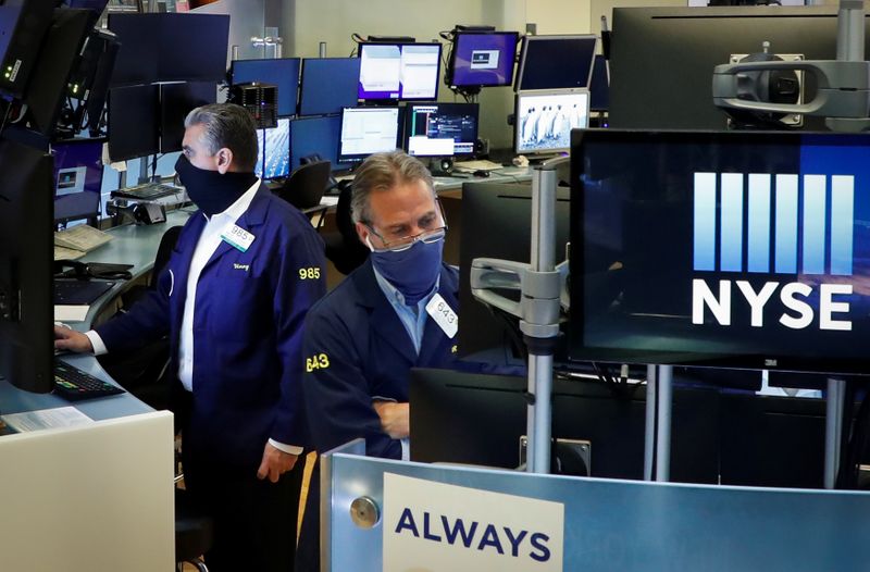 Traders wearing masks work, on the first day of in person trading since the closure during the
