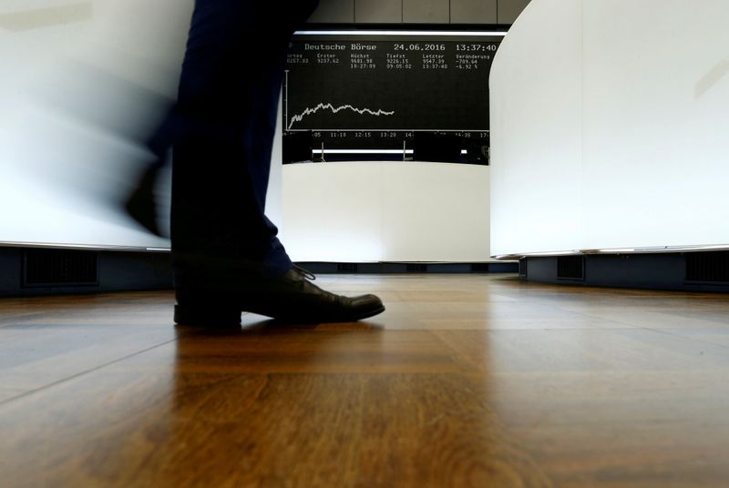 FILE PHOTO:  A trader walks past the German DAX Index board on the trading floor at the