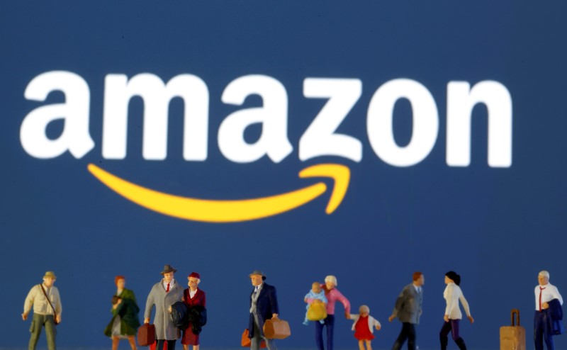 FILE PHOTO: Small toy figures are seen in front of diplayed Amazon logo