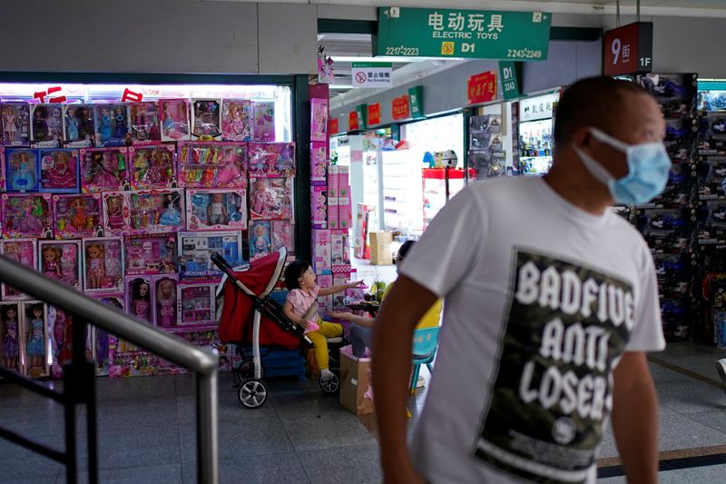 A man wearing face mask walks past a toy products stall at the Yiwu Wholesale Market following