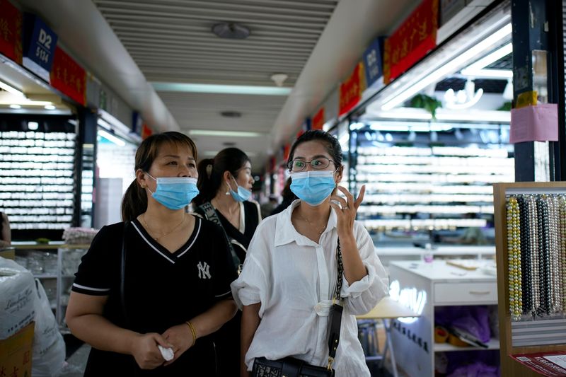 Women wearing face masks talk at the Yiwu Wholesale Market following an outbreak of the novel