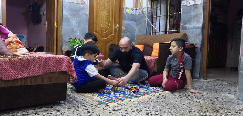 Local worker Muhammad Subeih Haider plays with his children at his home in Basra