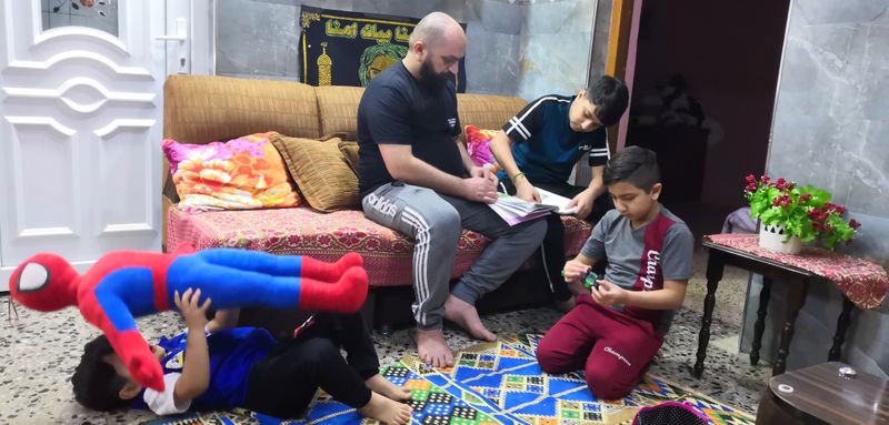 Local worker Muhammad Subeih Haider plays with his children at his home in Basra